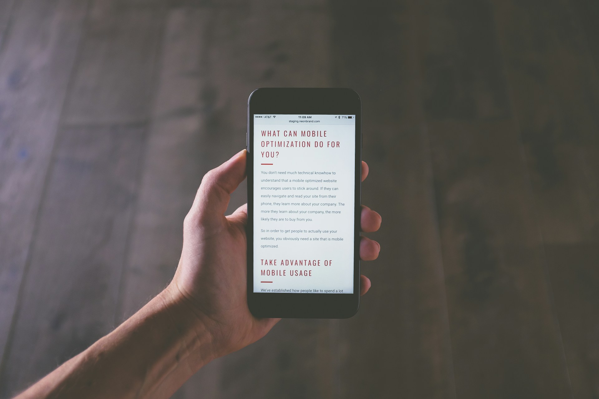 Une main tient un téléphone affichant la version mobile d’un site internet.